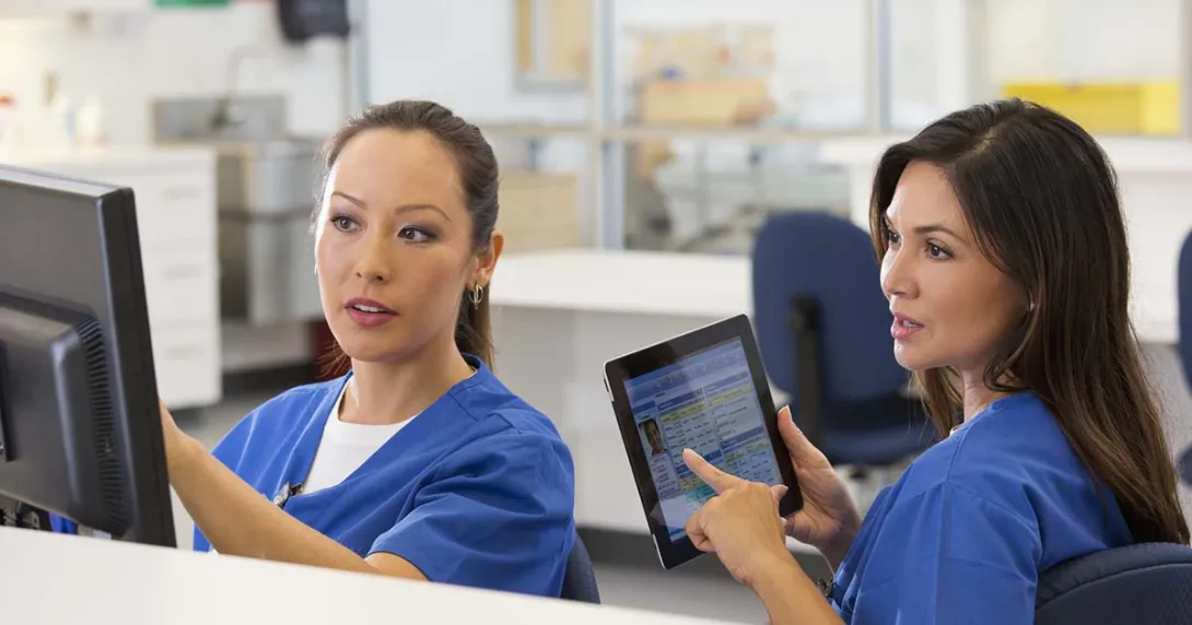 Nurses confer at computer screen