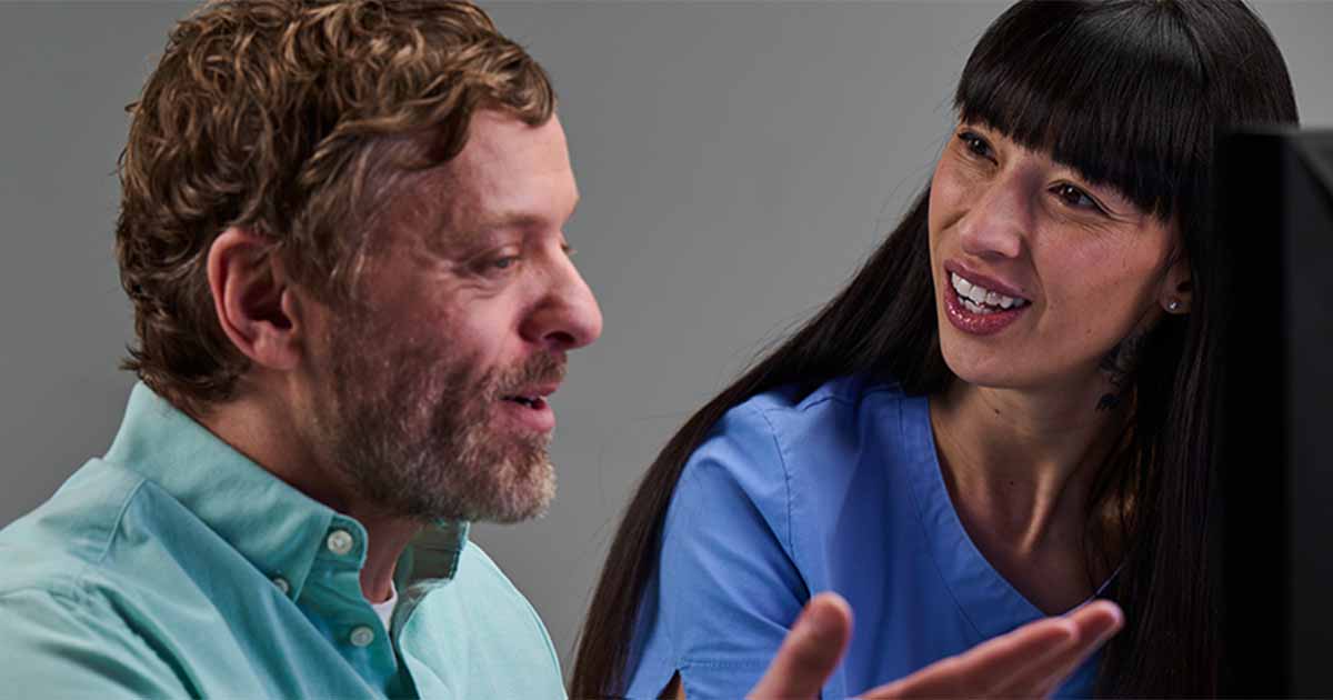 People talking in front of a computer monitor