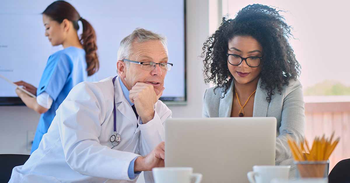 Doctor and businessperson looking at laptop screen