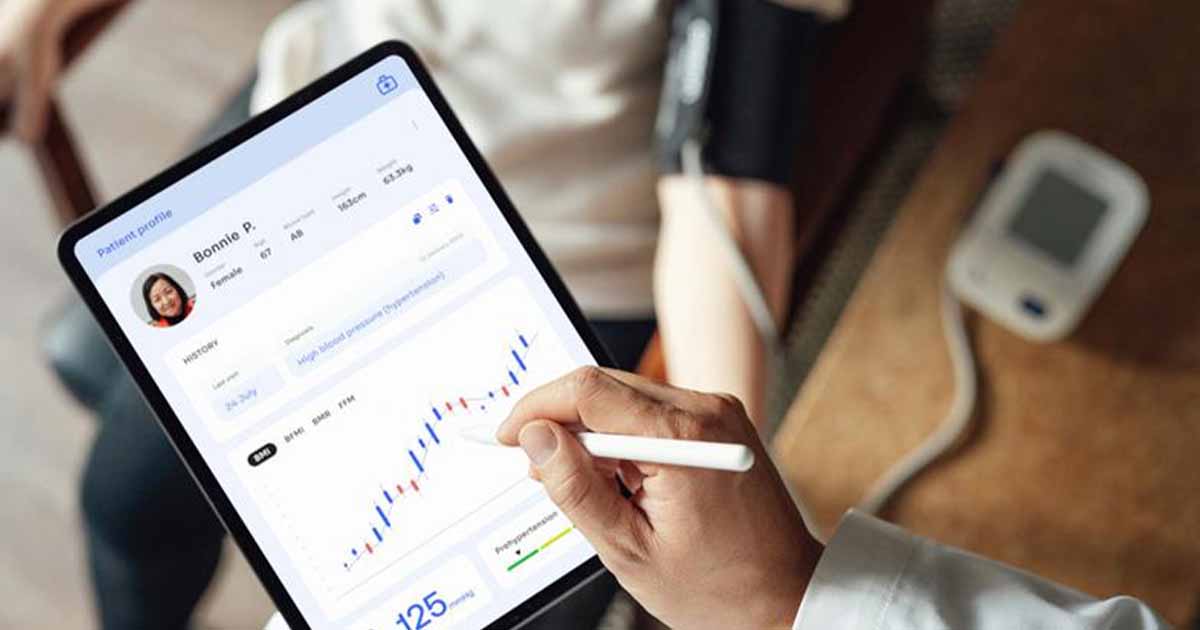 Healthcare worker looking at medical record on tablet with patient in background