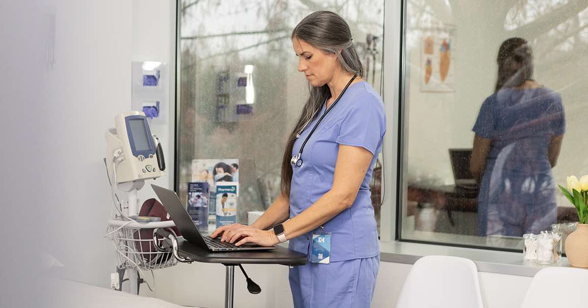 Healthcare worker using laptop in hospital room