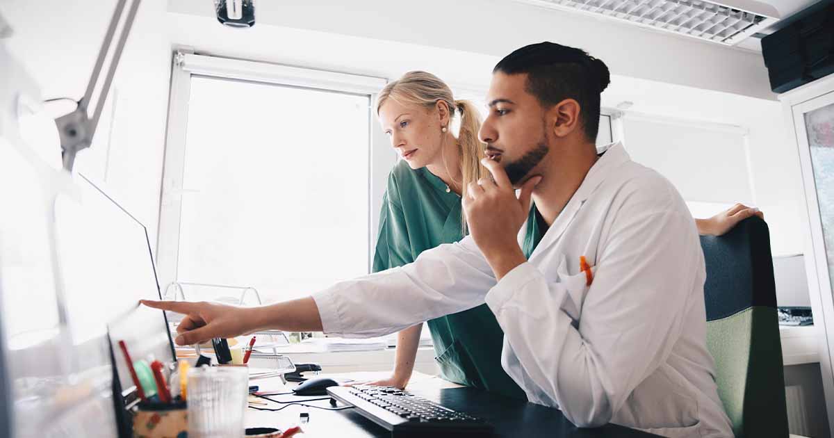 Healthcare worker pointing at a screen in conversation with colleague