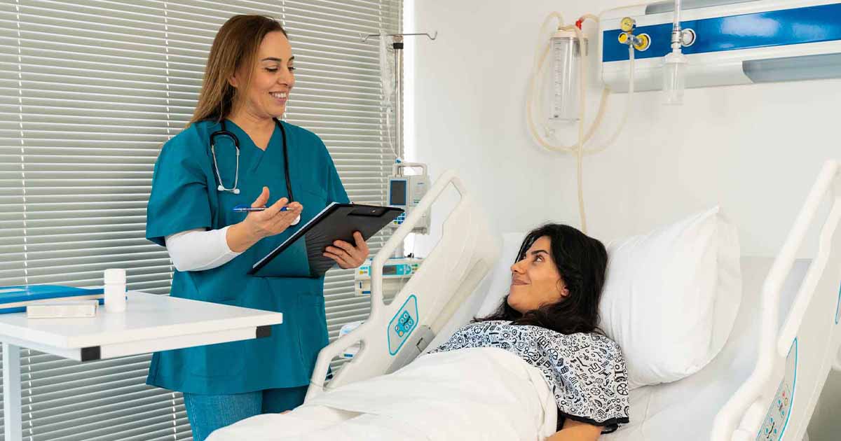 Doctor with clipboard talking to patient in hospital bed