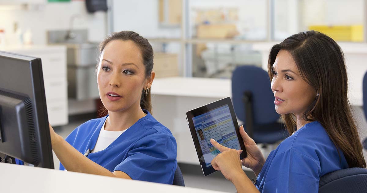 Two nurses confer about clinical documentation