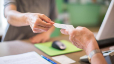 Person behind a desk handing a slip of paper to another