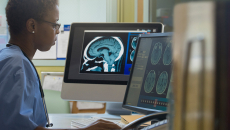 Healthcare worker with MRI image working on a computer