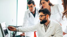 Group of clinical researchers gather around an EHR