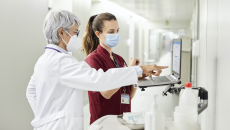 A doctor and nurse using a laptop along the hospital corridor