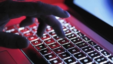 Hand on a laptop keyboard in red light
