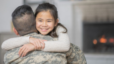 A parent in a military uniform hugging their child