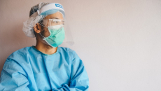 A clinician in PPE leaning against a wall