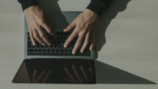 Overhead view of hands working on a laptop