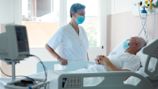 A COVID-19 patient speaks to a doctor, both in masks