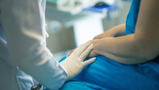 Doctor puts gloved hand on patient hand during examination  