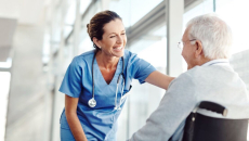 Caregiver and patient in a wheelchair smile at each other