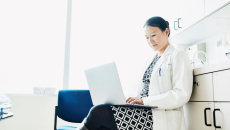 Clinician works on her laptop in a patient room.