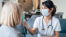 A clinician in a mask checks the oxygen of a patient at a community clinic.