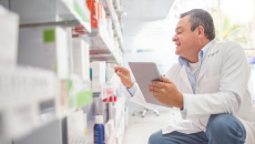 Male pharmacist bends to review a boxed medication at a specialty pharmacy.