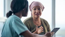 A nurse discussing a cancer patient's treatment plan using a digital tablet