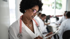A doctor using a tablet with a doctors' conference at the background