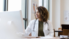 A doctor reviewing a patients medical file on a desktop computer