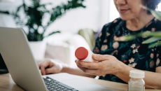 A patient holding prescription medicine in an online consultation with a doctor