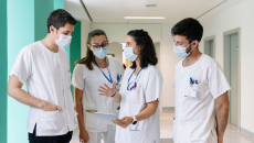 One healthcare worker talks with colleagues and references data on a tablet.
