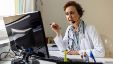A doctor facing a desktop computer in an online consultation