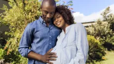 Person with hand on pregnant person's belly