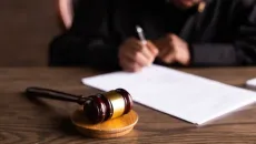 judge hand signs paper order at desk with gavel