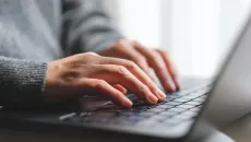 Hands typing on laptop
