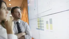 Businesspeople looking at graphs on a projector screen