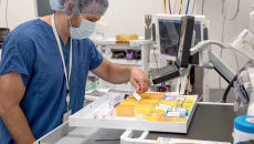 Lab worker in scrubs and mask sorting medication