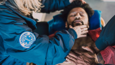 A man lays on a stretcher and receives care from EMTs 