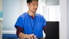 A nurse accessing a patient's record on a laptop computer