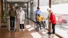 Nurses and post-acute facility patients walk in a hallway