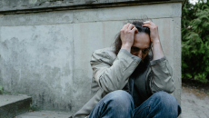 Homeless man holds head