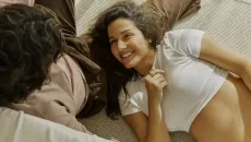 Person lying on a couch with another person sitting next to them