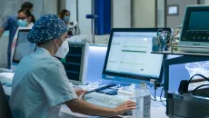 Hospital clinician reviews patient data against printed readout 