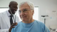 Doctor listens to older male patient's heart with stethoscope 