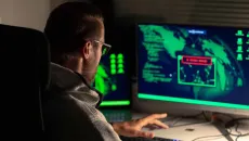 Hacker reviews a map on a monitor