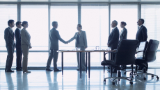 Officials in suits shake hand in closing a deal