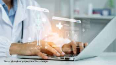 Doctor using laptop with CGI icons overlaid