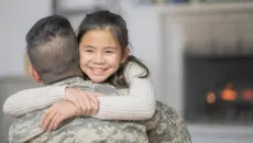 Army service member hugs child
