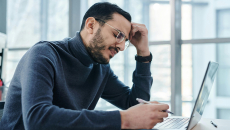 Frustrated man with glasses at a laptop