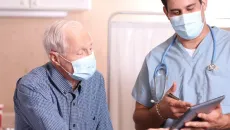 Doctor reviews information with an elderly patient on a tablet