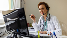 A doctor wearing a headset with a microphone in virtual consultation with a patient