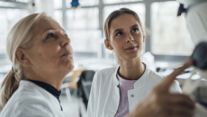 Two healthcare workers looking up at a monitor