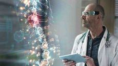 Healthcare worker with tablet looking at a digital display of a human spine