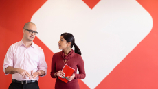 A man and a woman appear talking in front of the CVS Health logo.